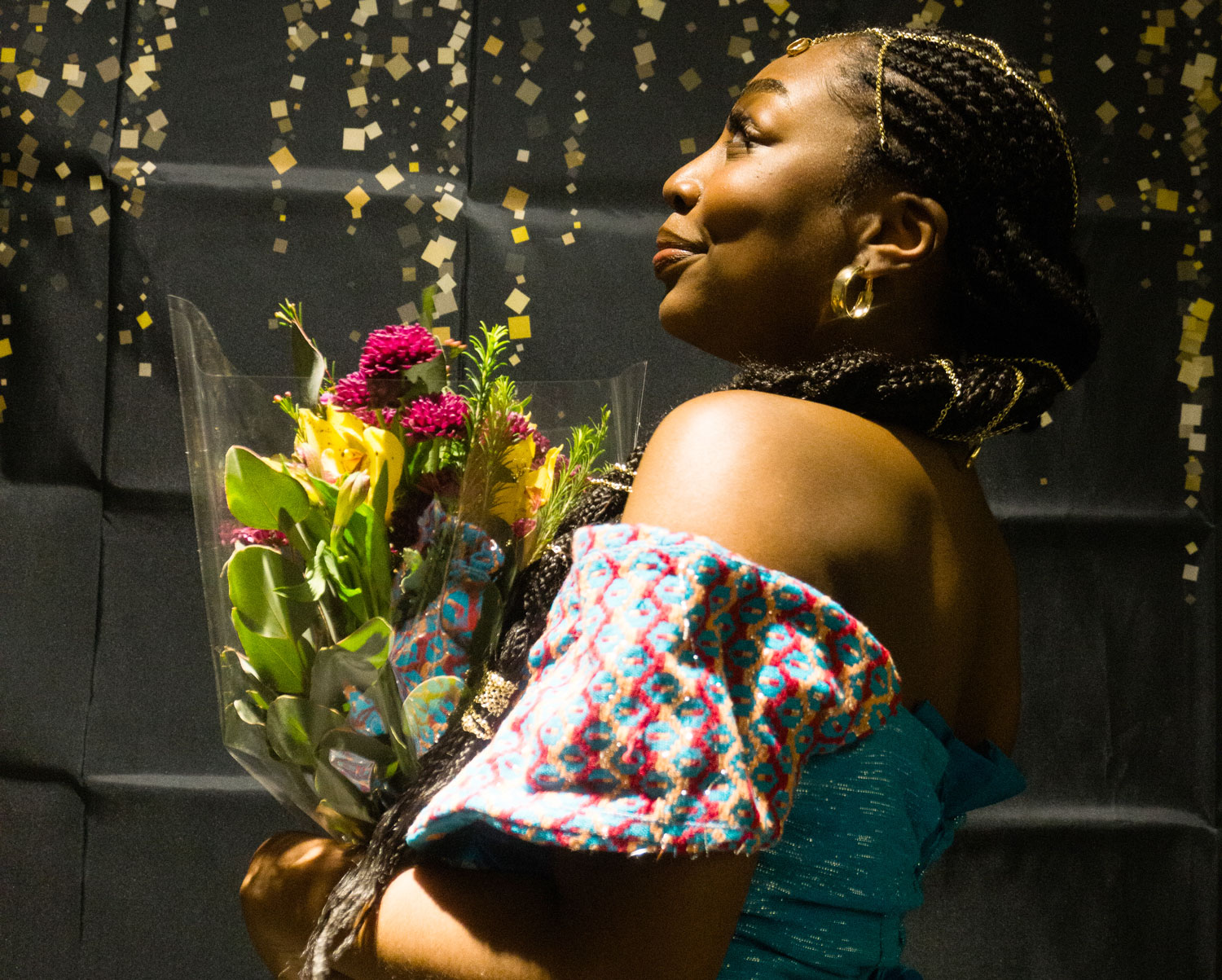 Picture of Cassie Bonah holding flowers, dressed in traditional Ghanaian attire and facing to the side