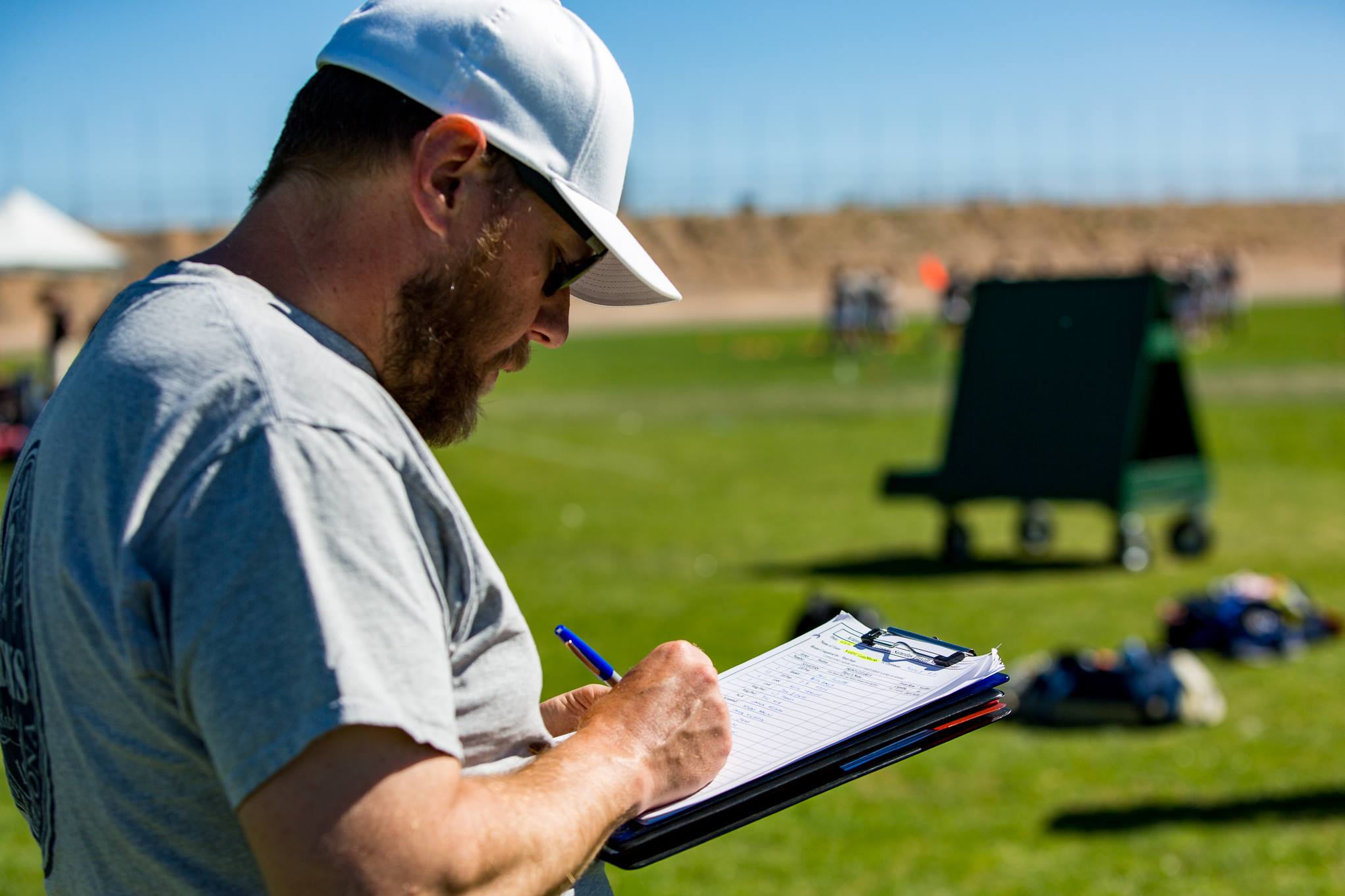 Matt Fahy on a rugby field writing on a clipboard.