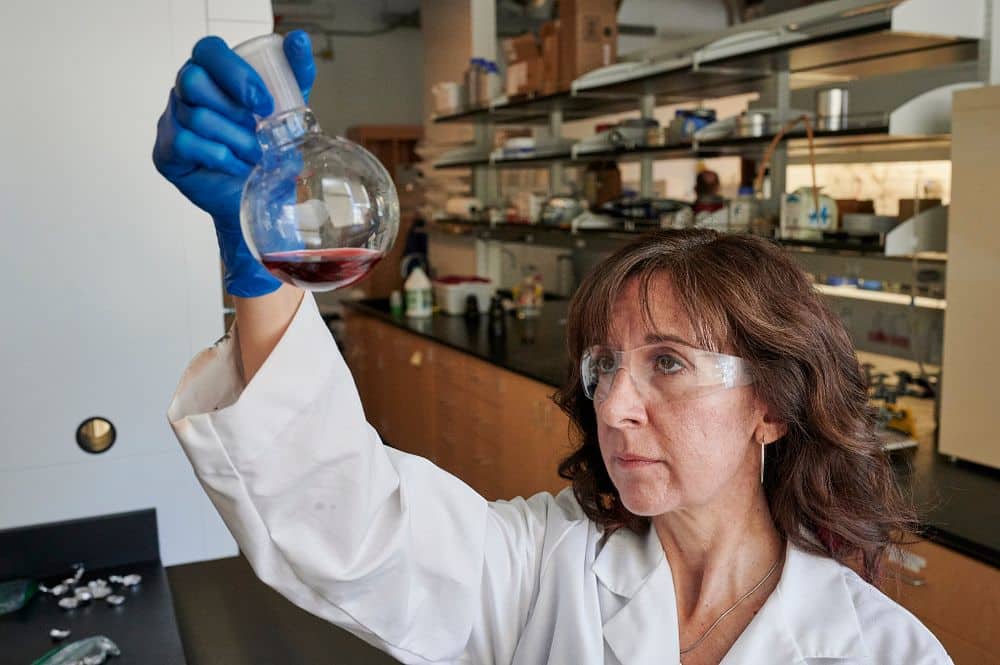 Cindy Browder in a lab looking at liquid in a beaker.