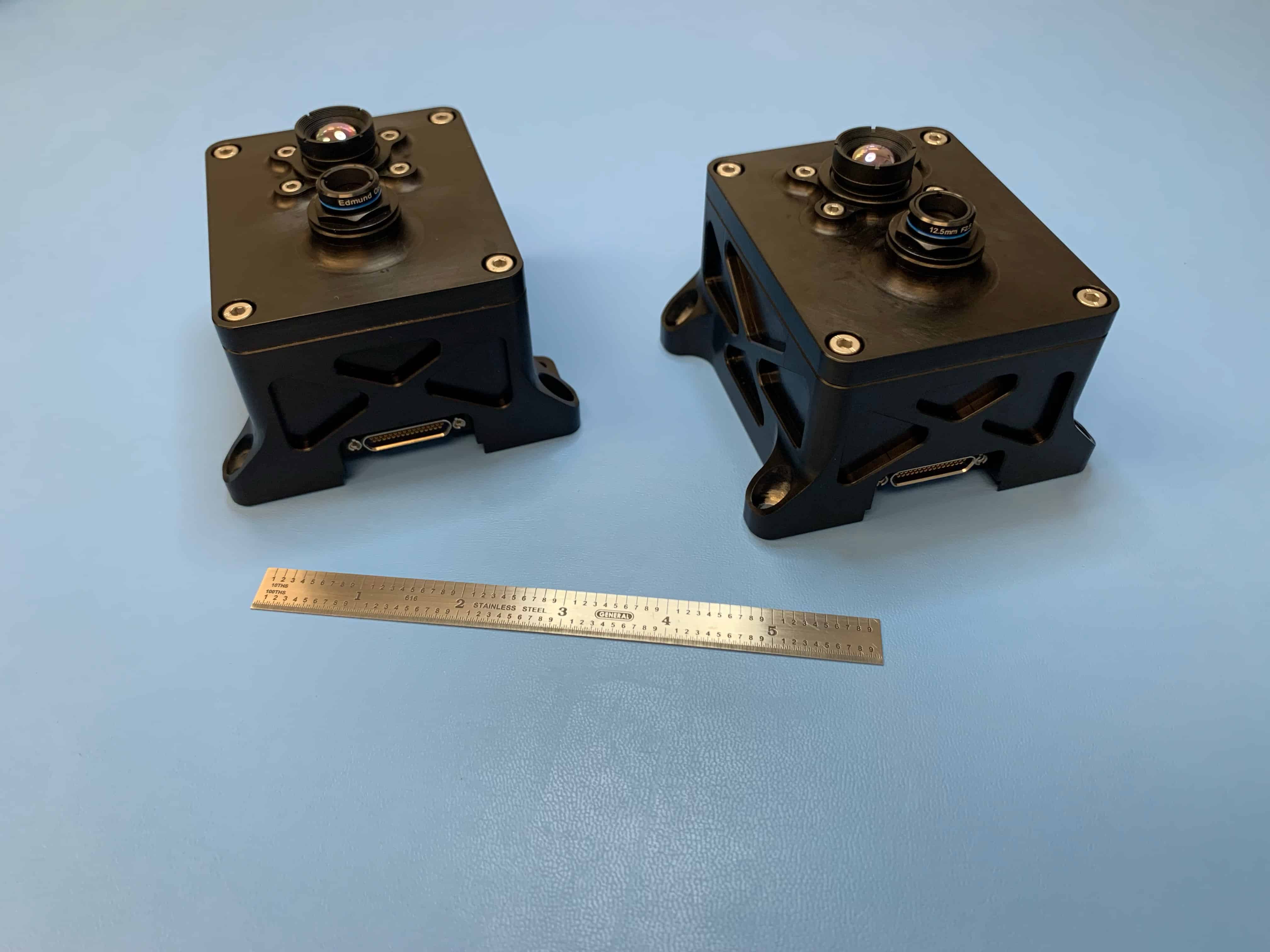 Two VISIONS cameras (square black boxes) against a blue backdrop.