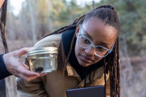 Student examining a jar during an ecological research project