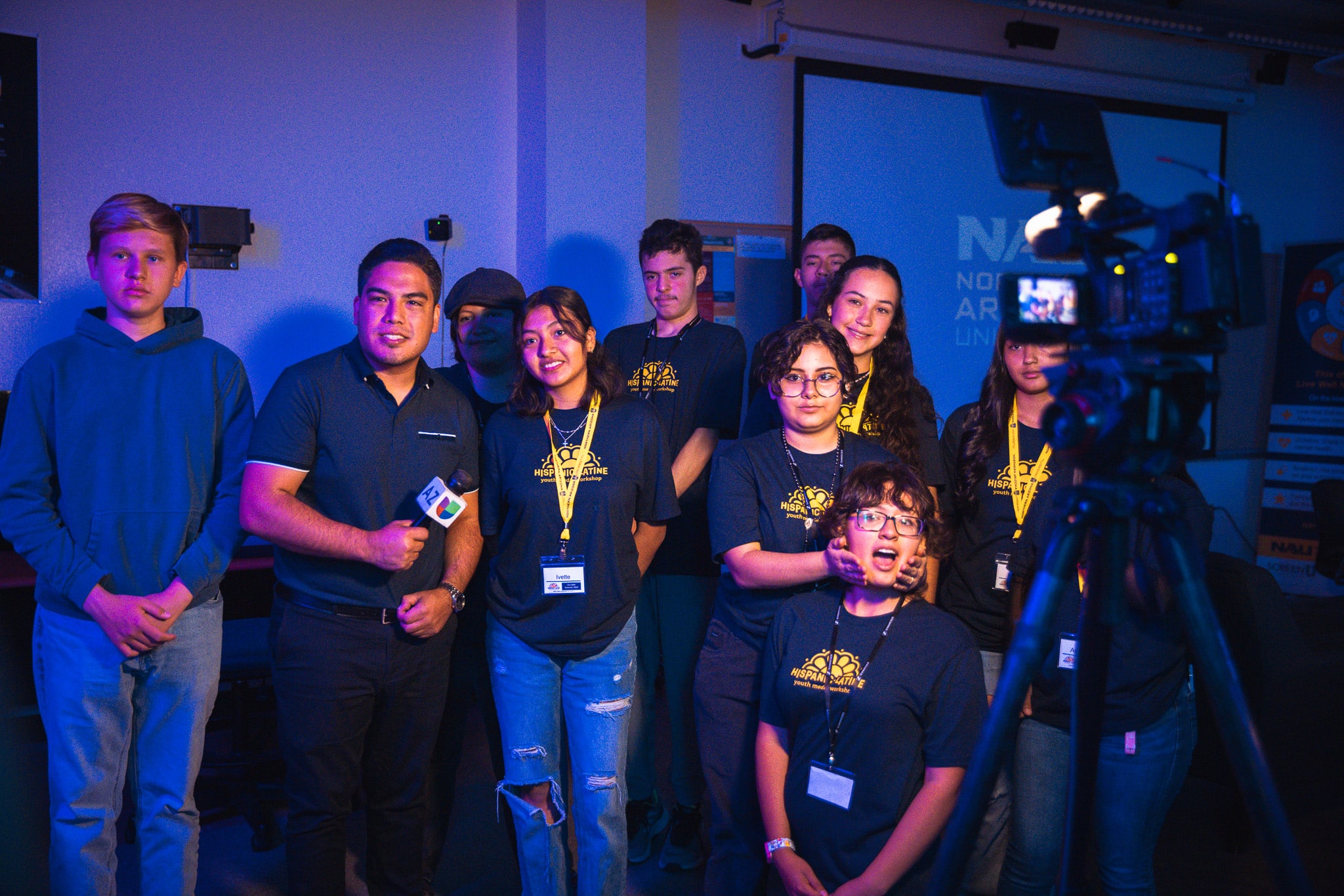 Univision reporter Hector Lagunas and Flagstaff Unified School District students pose with a video camera in a blue room.