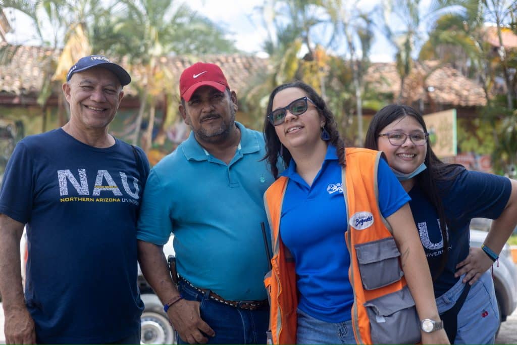 Kimberly Higuera posing with other NAU staff in front of palm trees