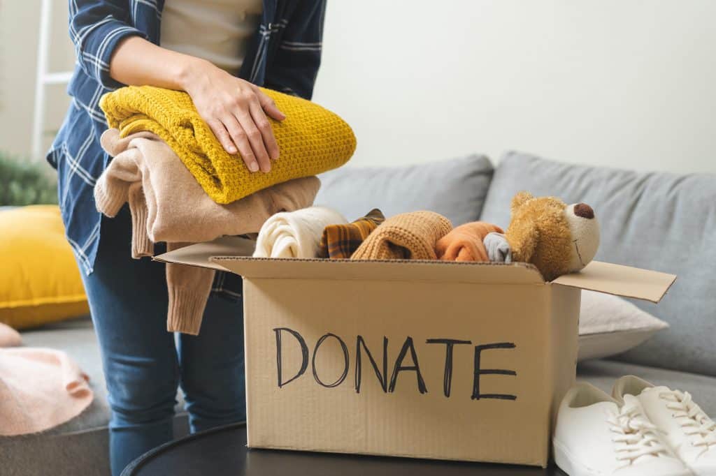 Donation box sits on table while person adds items