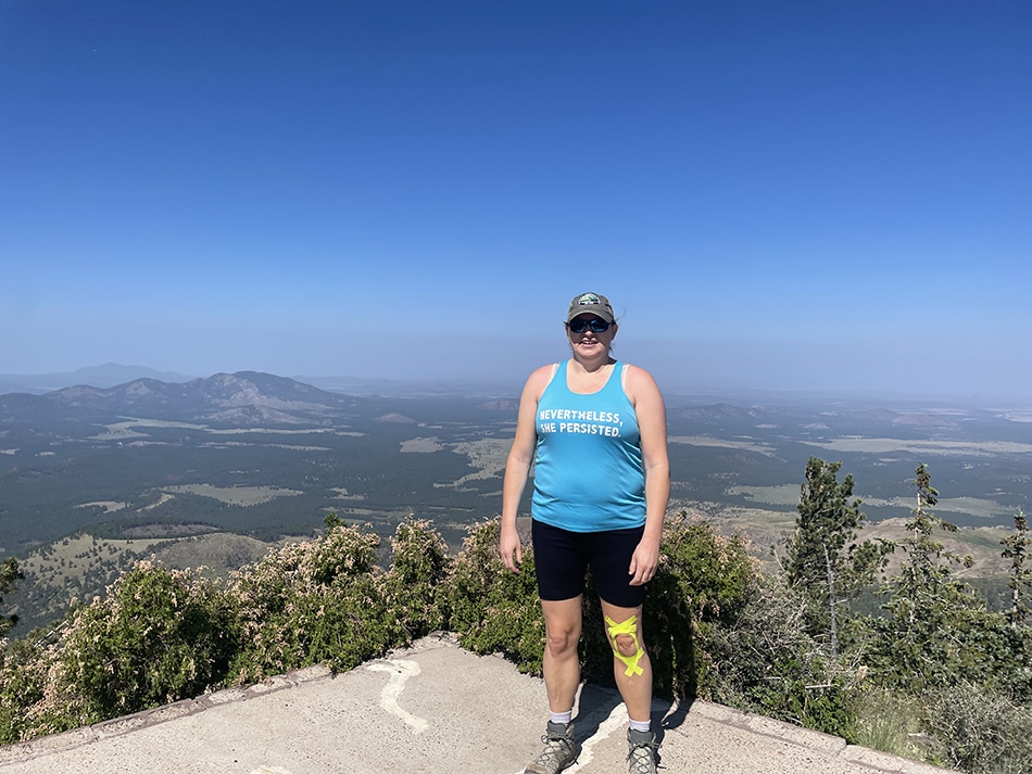 A woman in hiking clothes on top of Kendrick Peak.