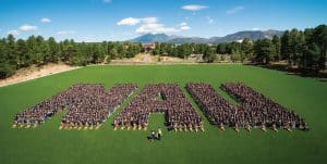 Students standing on a sports field wearing matching T-shirts and forming the letters NAU