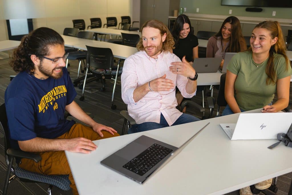 Robert Wickham sitting at a table with graduate students and their laptops