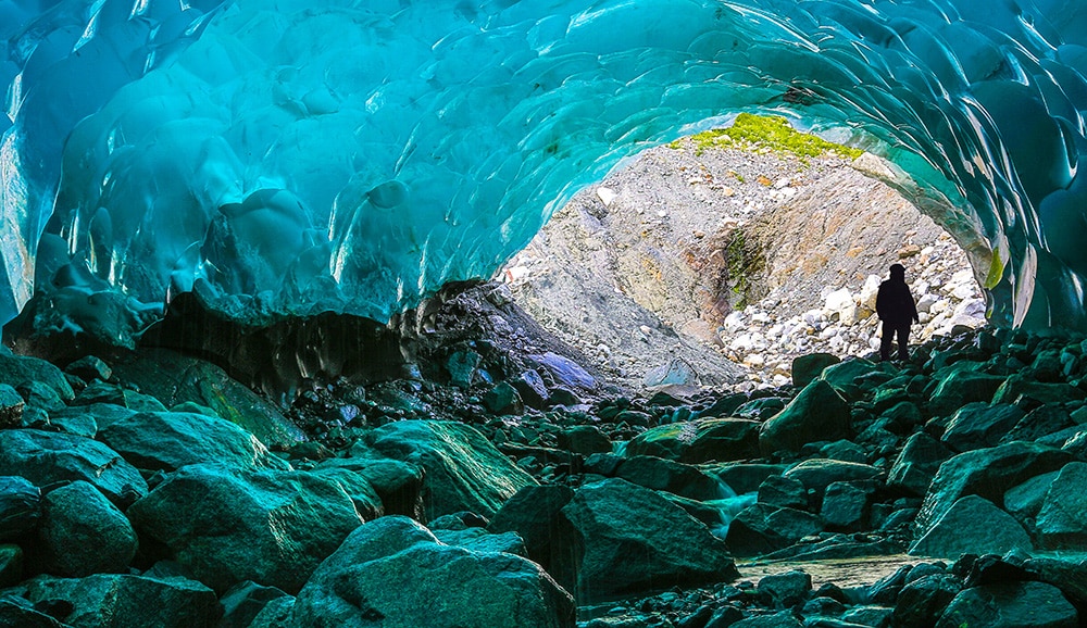 A man at the entrance of Mendenhall Glacier Ice Cave, Juneau, Alaska