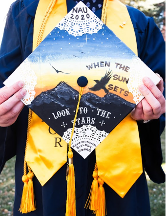 A graduation cap decorated with mountains and a sunset that says, "When the set sets, look to the stars."