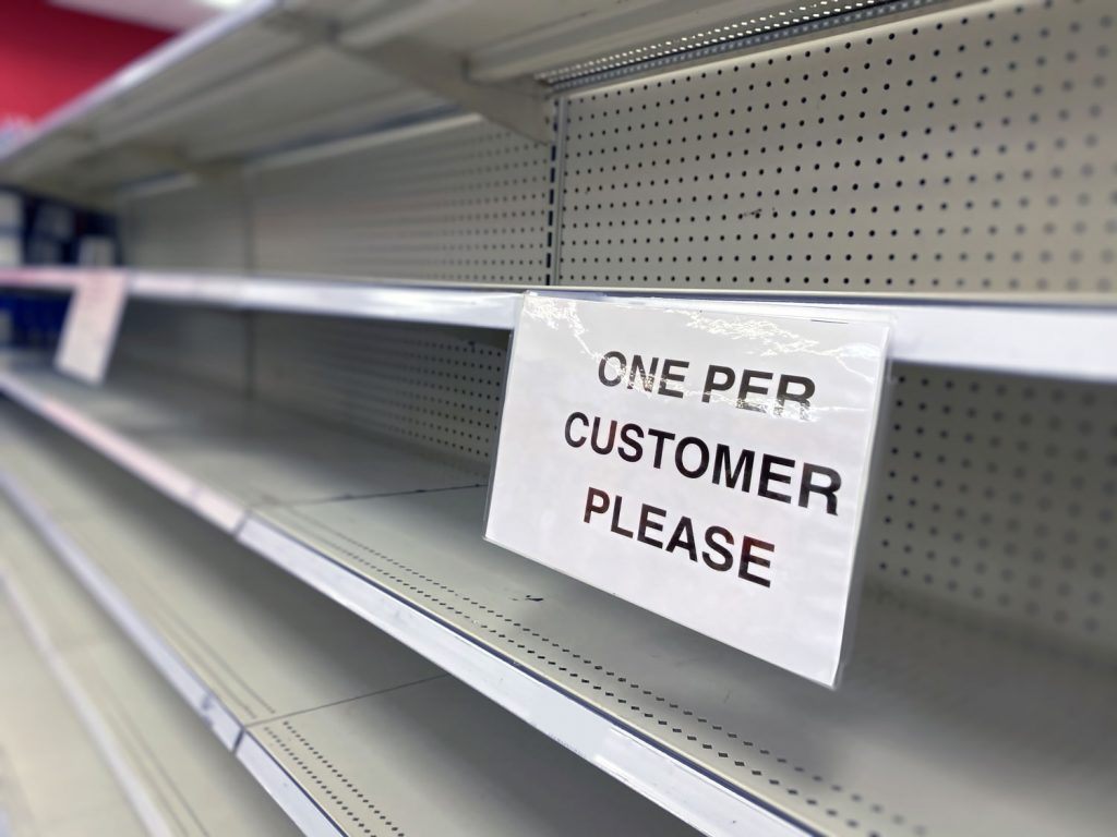 empty shelves with a sign that says "one per customer please"