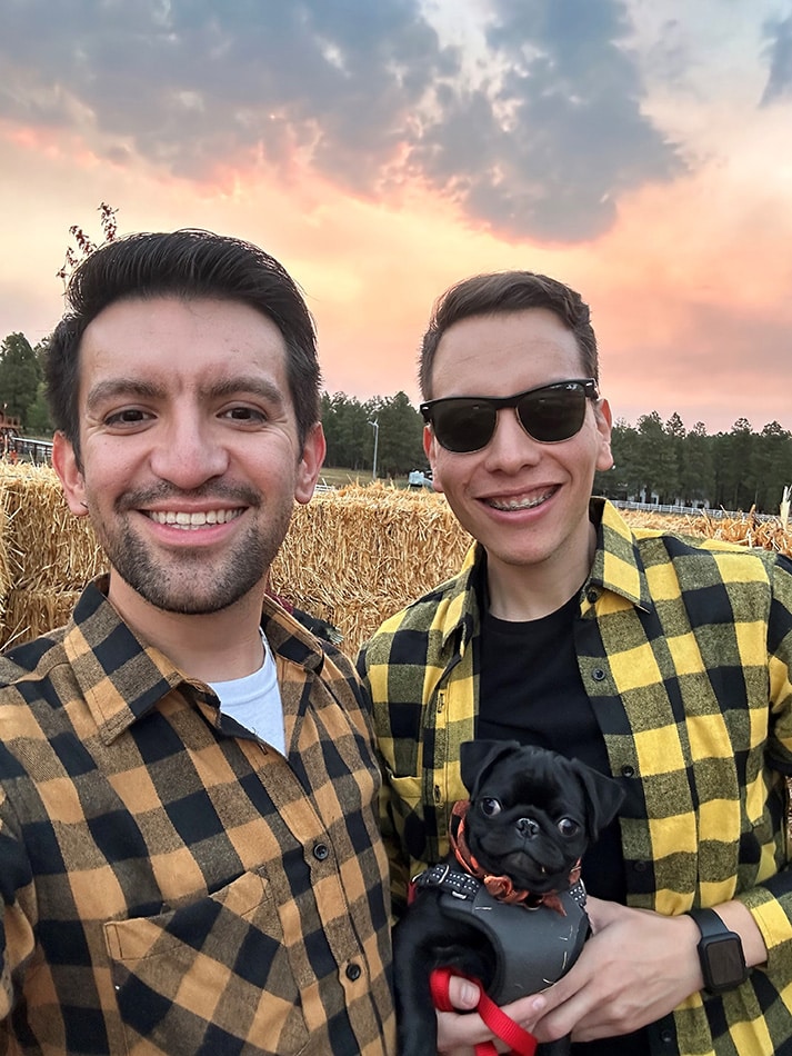 Salvador Lopez and his partner wearing flannel in a cornfield with their pug