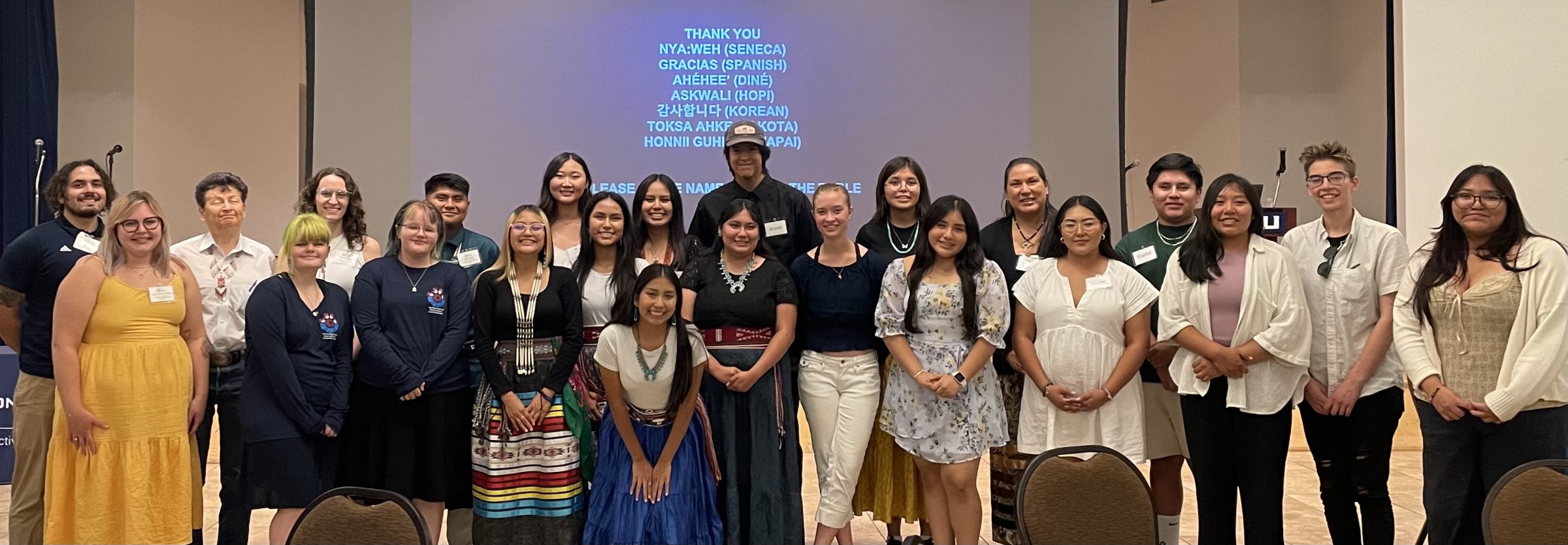 CARE students and staff members gather in front of a blue projected screen in an NAU conference room.