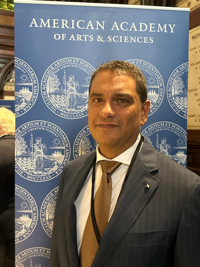 President Cruz Rivera standing in front of an American Academy of Arts and Sciences sign