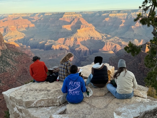 students sitting on rocks at the South Rim of the Grand Canyon with notebooks