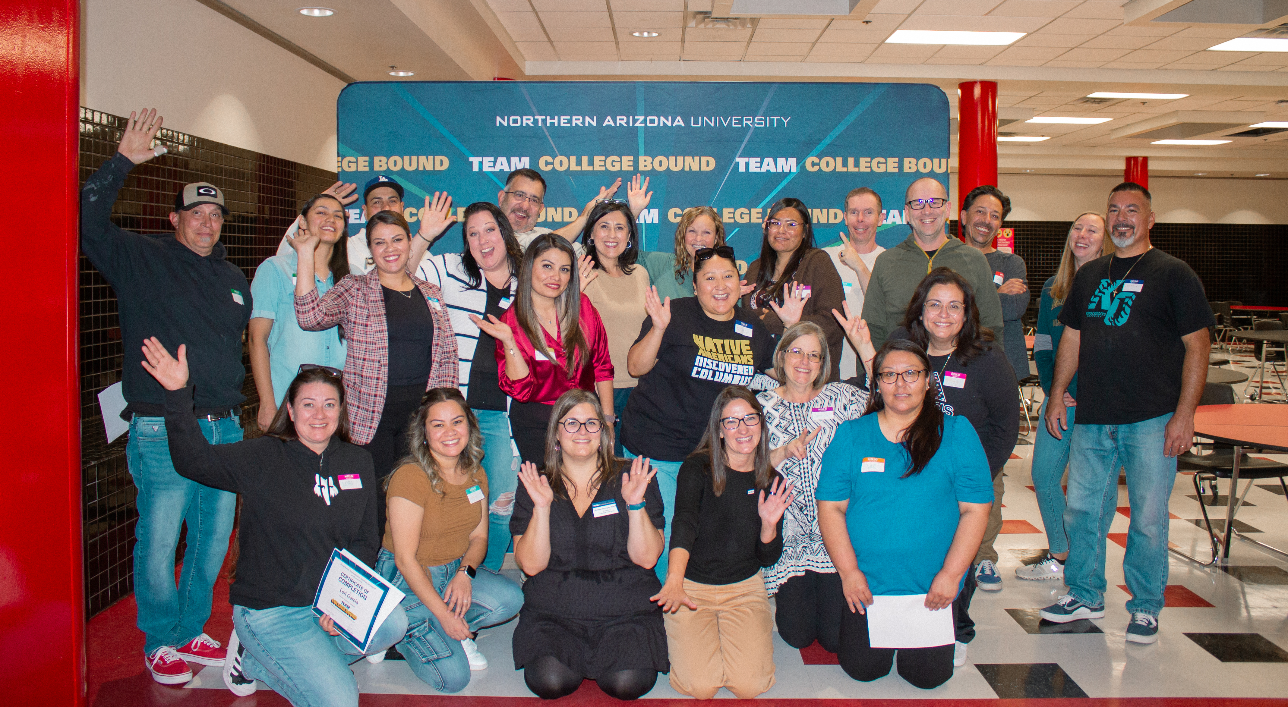 Team College Bound families and faculty pose in front of a blue backdrop in Coconino High School.