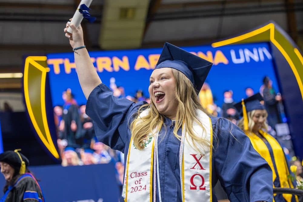 An NAU graduate celebrates after receiving her diploma.