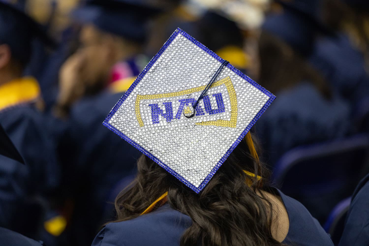 graduate wearing a bedazzled graduation cap with NAU logo