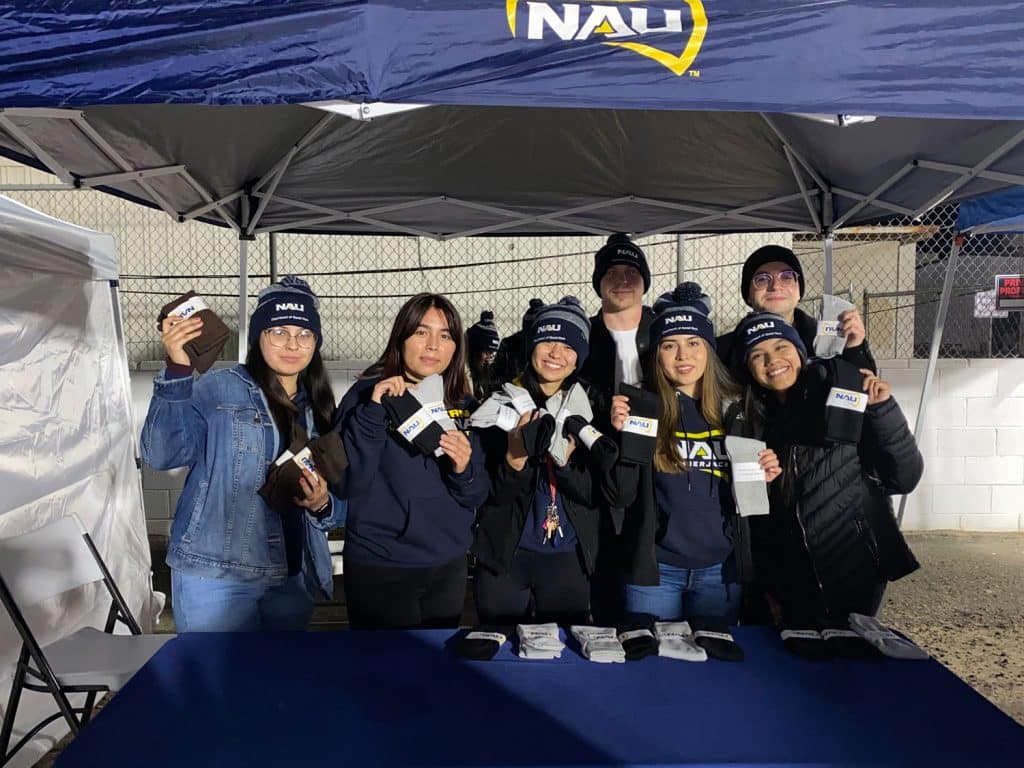 Jocelyn Andrade and fellow students standing behind a table holding socks 