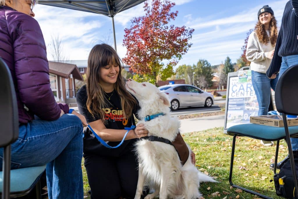 woman petting a fluffy white dog under a tent