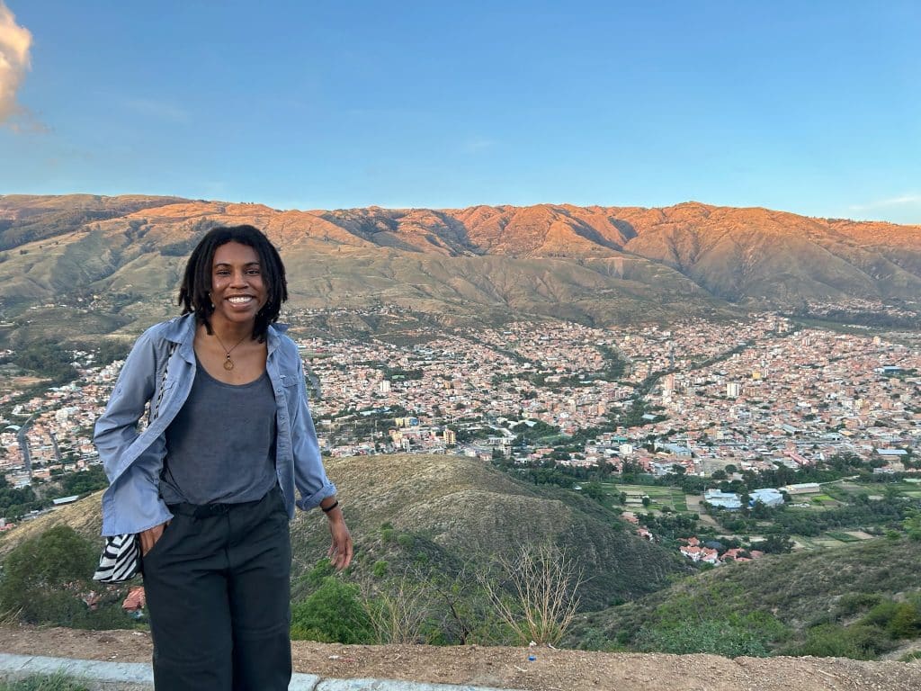 Elizabeth Randolph posing at a viewpoint above a city surrounded by mountains