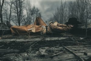 Photograph of cowboy laying on the tracks of a burning forest