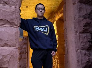 Civic Gomes standing in a stone doorway wearing an NAU sweatshirt
