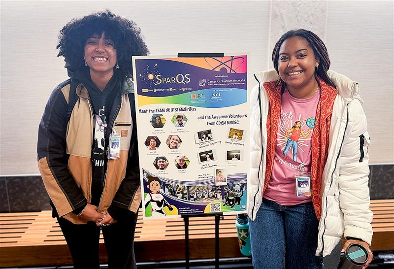 Two women stand by a SparCQS board.