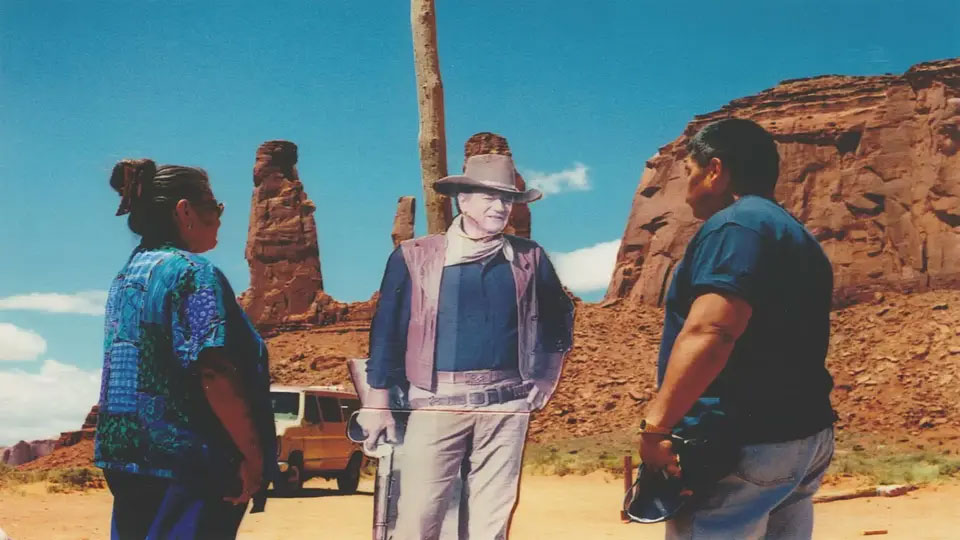 Two people staring at a cardboard cutout of John Wayne at Monument Valley