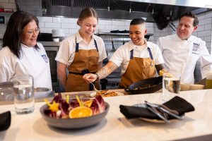Two instructors and two students going over how to finish decorating a plate