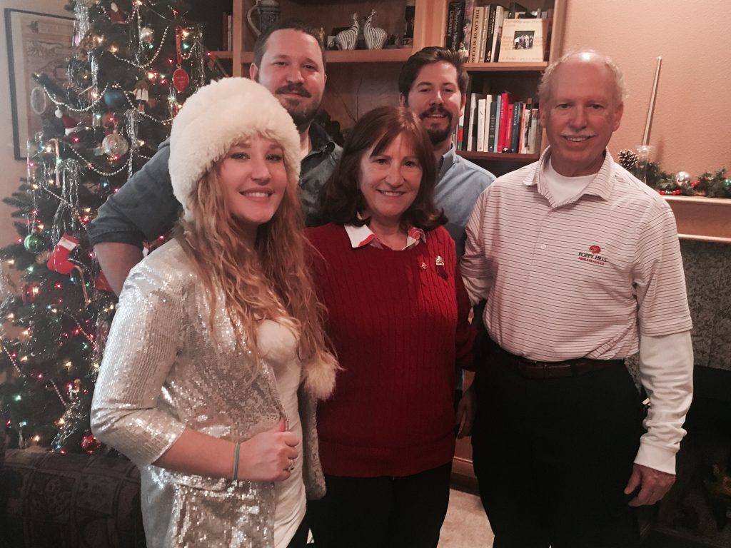 William Alger posing with his wife and three kids in front of a Christmas tree and library 