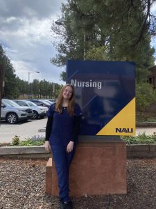 Melanie Rice in navy scrubs standing in front of the College of Nursing sign.