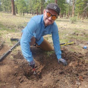 Caelum Mroczek digging a hole with a spade in a forest