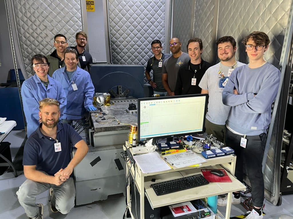 group of students and faculty standing in a lab with cameras and testing equipment