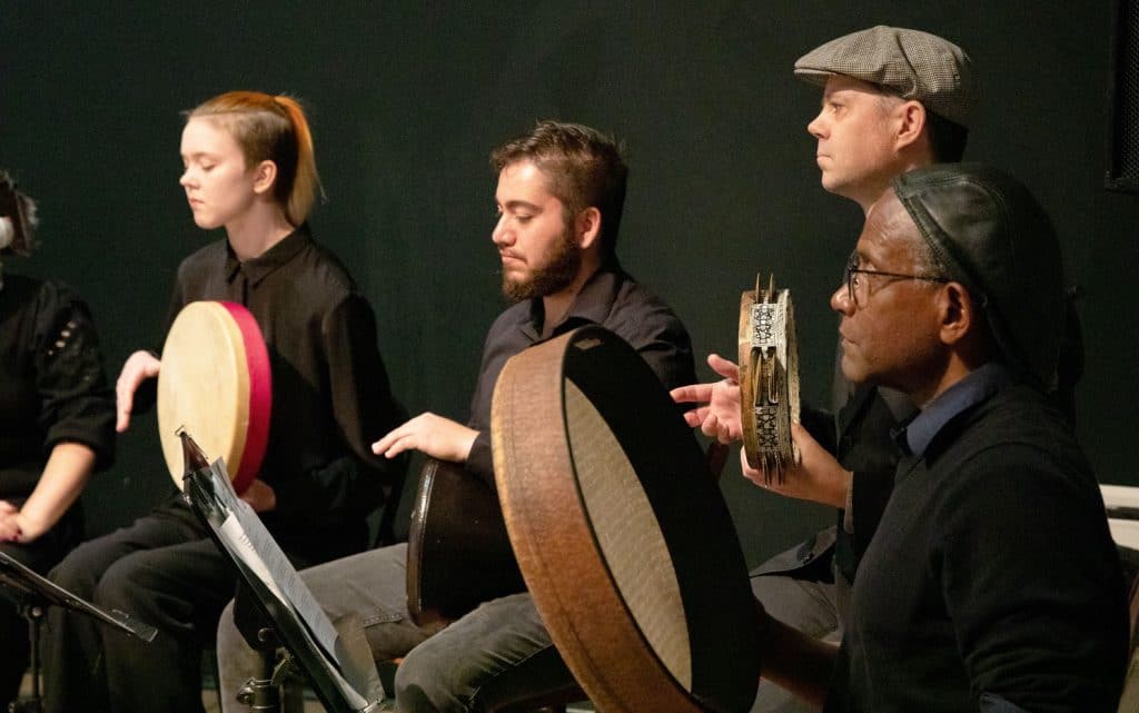 Four people playing hand drums