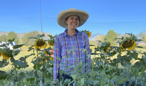 Gayle Gratop standing on her farm with sunflowers behind her