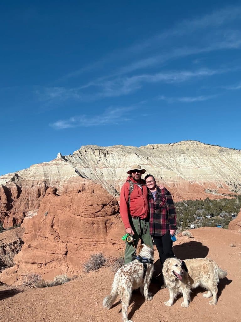 Jeff and Whitney McKay with two dogs in front of red rocks