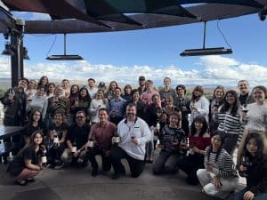 Group of NAU Hospitality students posing on a winery in Cottonwood. Some are holding a cup of wine and others are holding bottles
