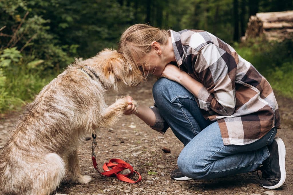 Woman kneeling with a dog and placing her forehead on his