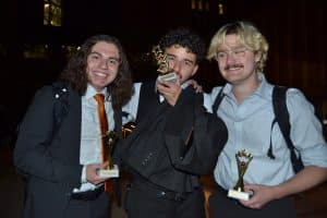 Three male members of Mock Trial Club pose with individual competition trophies.