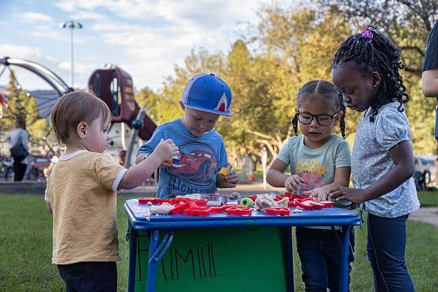 Kids standing around a craft table in an outdoor park