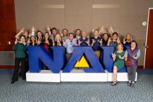 Group of employees throwing LJs in front of a large NAU sign