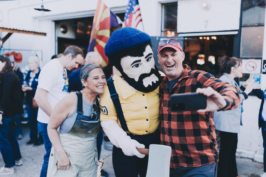 Two people posing with Louie the Lumberjack at Mother Road in Flagstaff