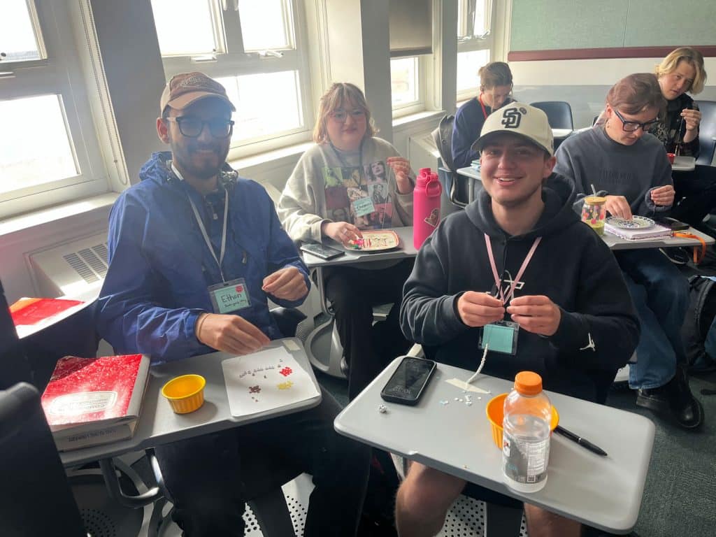 Students sitting at desks making friendship bracelets