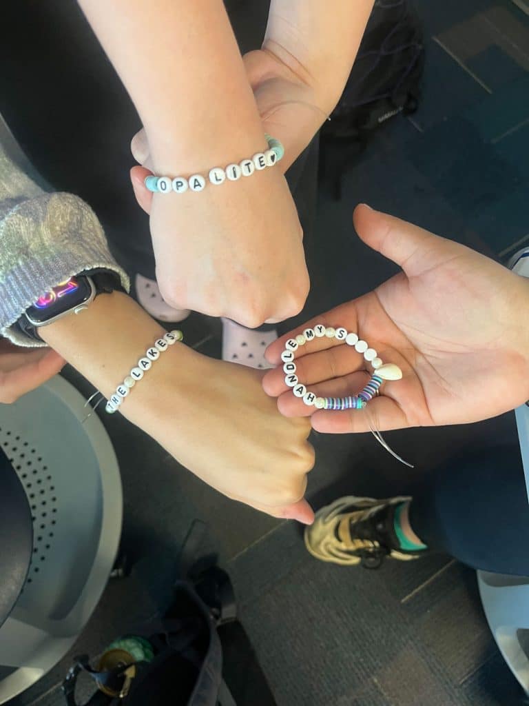 three friendship bracelets on wrists with Taylor Swift lyrics