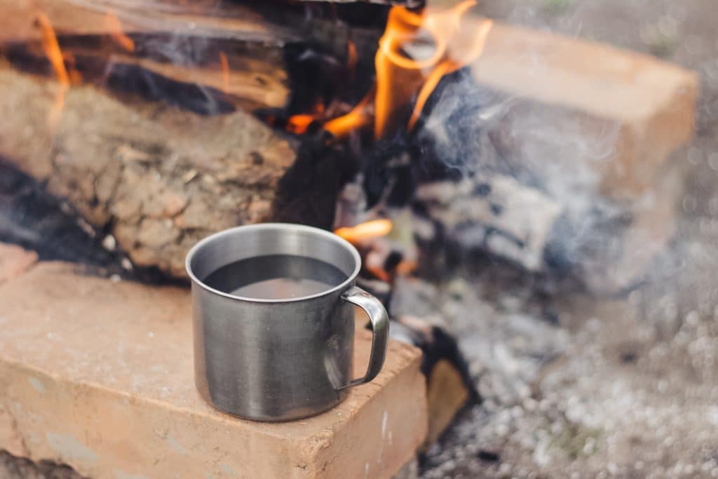 Cup of water on top of a wooden surface surrounded by smoke and fire