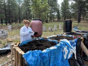 Woman working with soil next to a composting bin