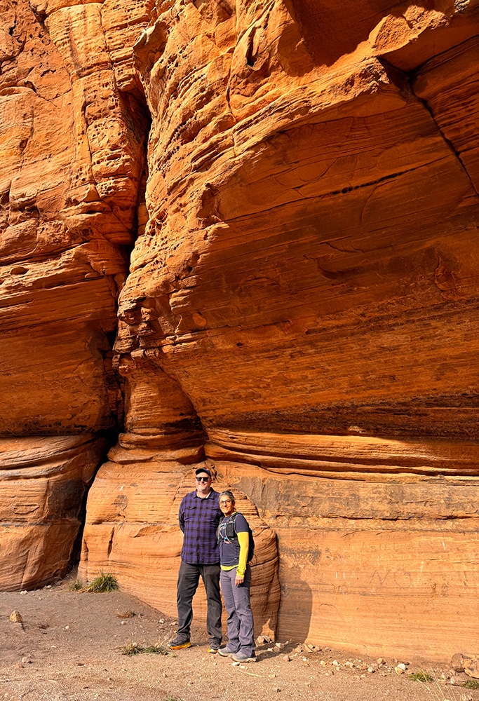 Aaron Kimbrell and his partner standing in front of red rock cliffs