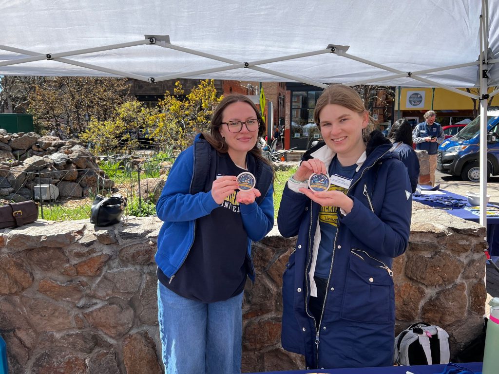Ellen Liebig and another woman holding up stickers at Science on the Square in Flagstaff